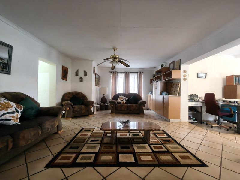Spacious open-plan living area featuring ceramic floor tiles, a central ceiling fan, and integrated built-in cabinetry, offering a versatile layout for family living.
