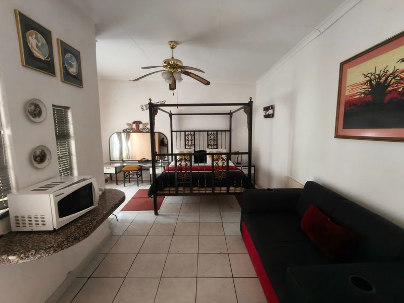 Spacious bedroom featuring tiled flooring, a ceiling fan, and a built-in vanity counter area.