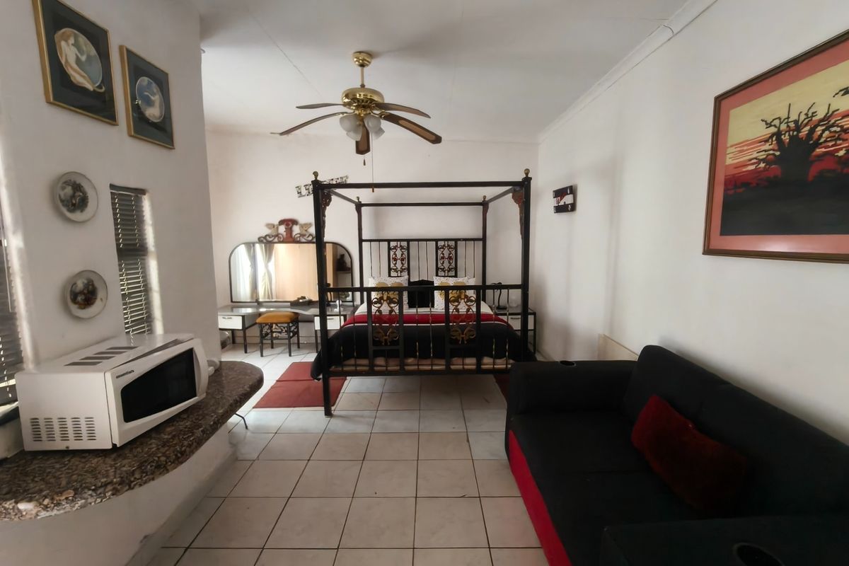 Spacious bedroom featuring tiled flooring, a ceiling fan, and a built-in vanity counter area.
