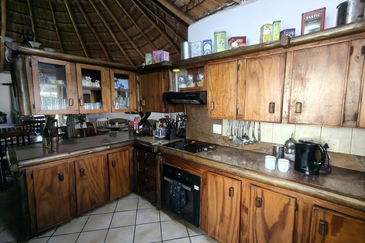 Rustic kitchen featuring wooden cabinetry, built-in oven, extractor fan, and unique thatch roof ceiling, offering a traditional farm-style aesthetic.