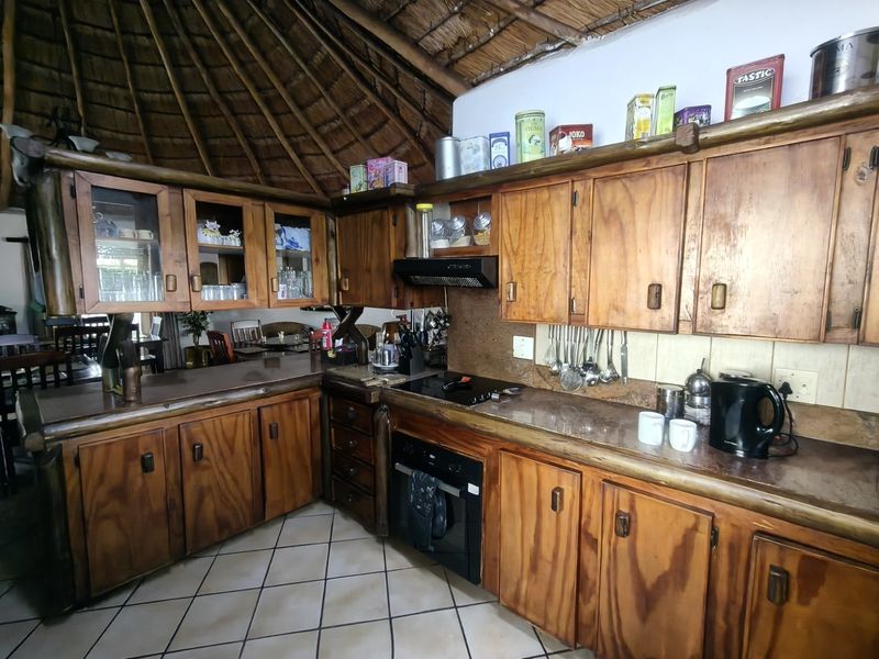 Rustic kitchen featuring wooden cabinetry, built-in oven, extractor fan, and unique thatch roof ceiling, offering a traditional farm-style aesthetic.