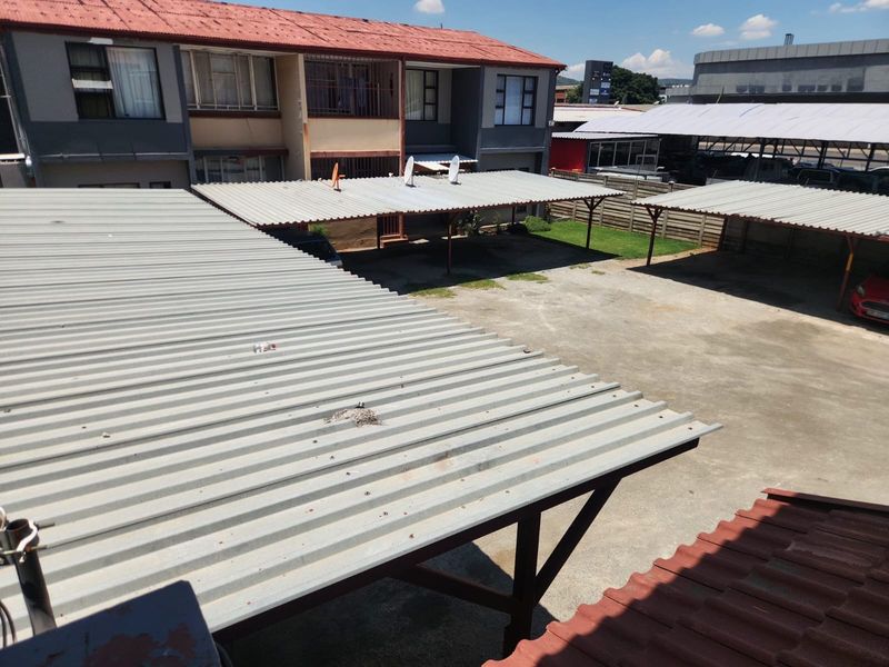 Elevated view of the apartment complex parking area featuring multiple corrugated metal carports and a paved driveway.