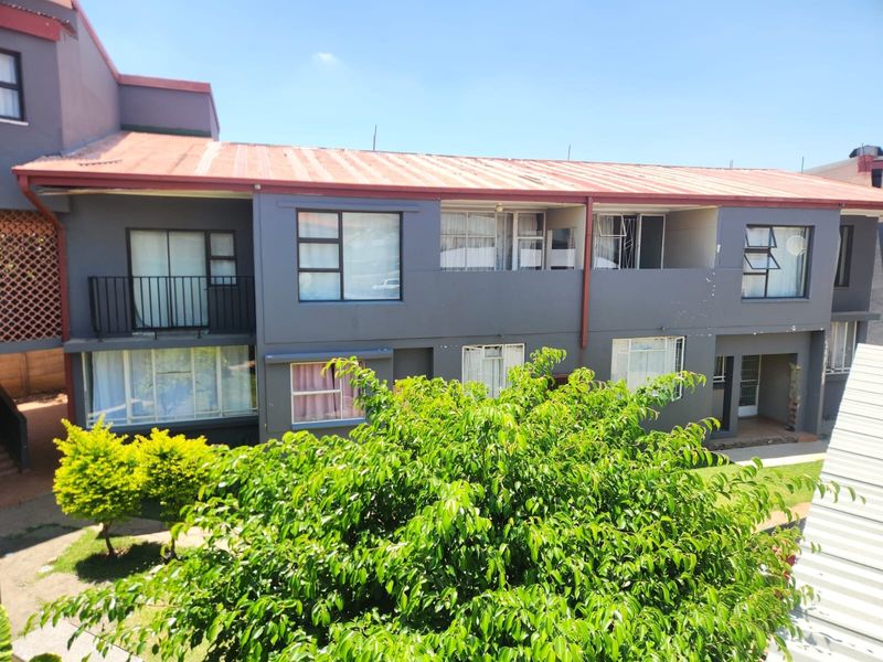 Exterior view of a multi-story apartment complex featuring a corrugated metal roof and balcony access, showing signs of exterior wear.