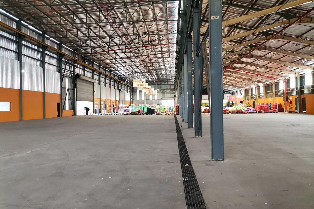 Spacious industrial warehouse featuring a high-clearance steel portal frame, polished concrete flooring, and integrated linear drainage, suitable for logistics or manufacturing operations.