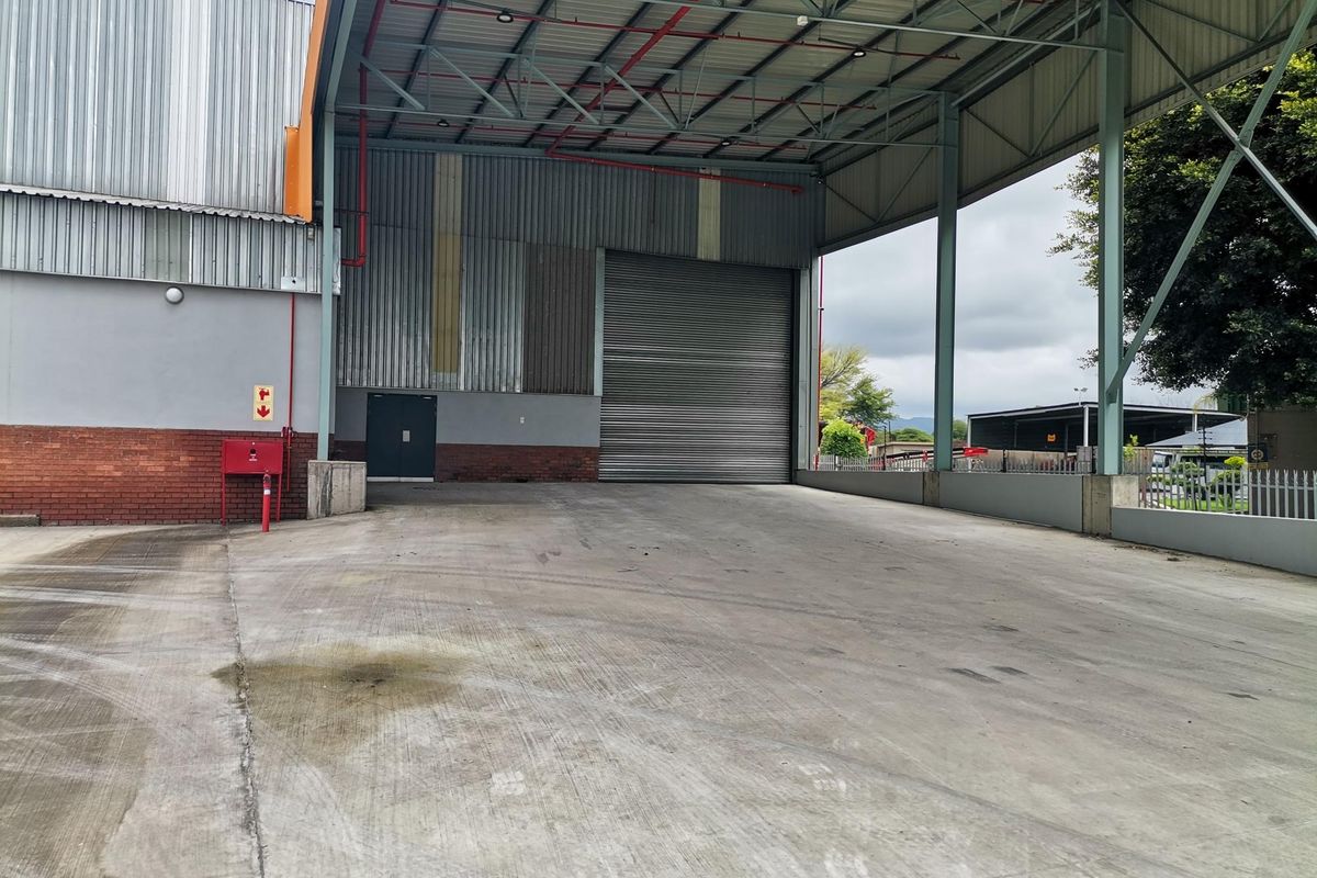 Industrial loading bay featuring a large roller shutter door, high-clearance steel frame canopy, and durable concrete flooring suitable for logistics and heavy vehicle access.