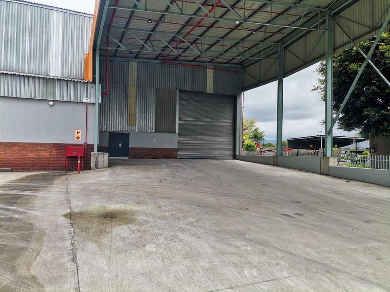 Industrial loading bay featuring a large roller shutter door, high-clearance steel frame canopy, and durable concrete flooring suitable for logistics and heavy vehicle access.