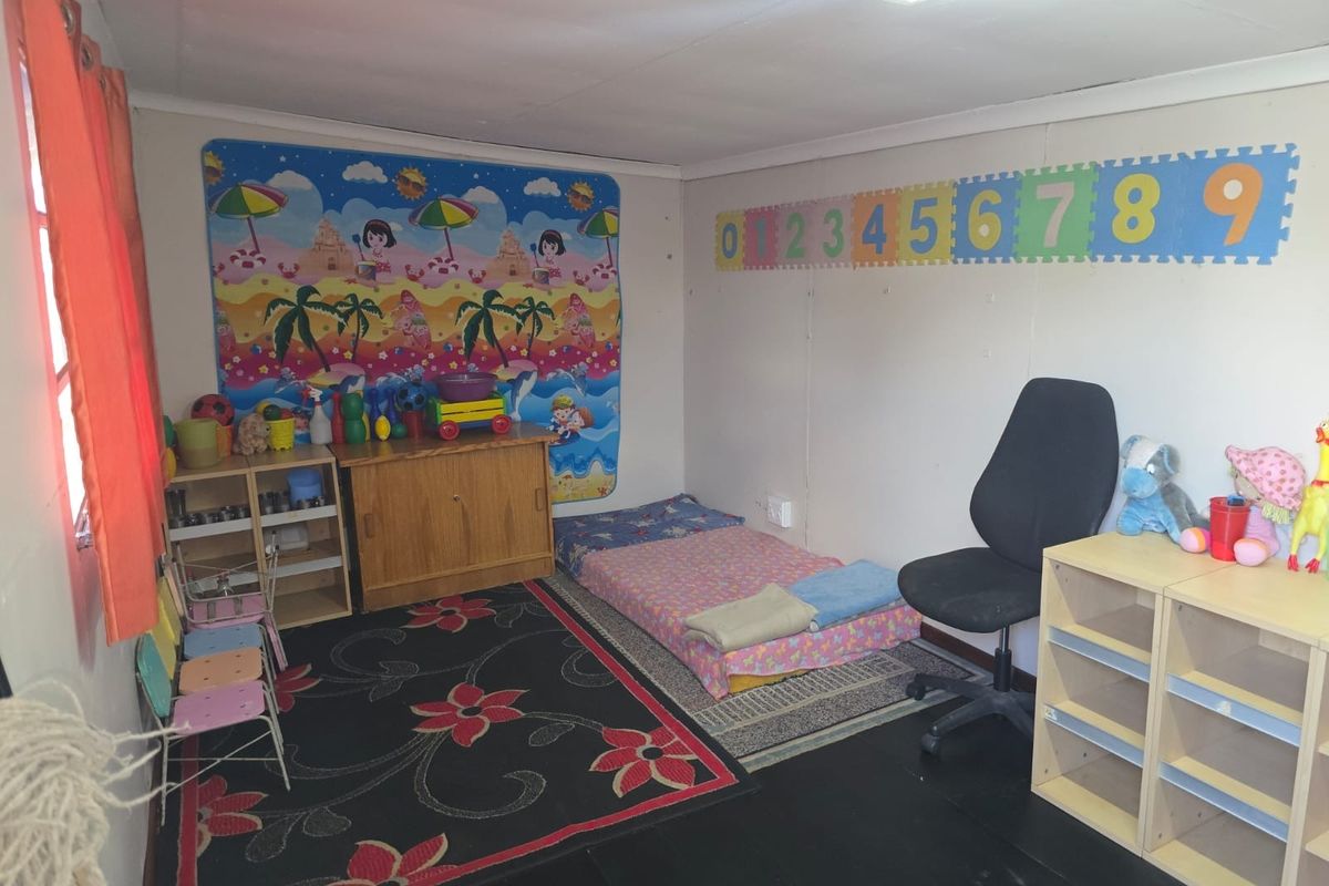 A functional bedroom space featuring painted wall panels and overhead lighting, currently utilized as a children's play and rest area.