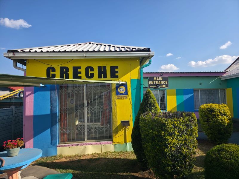 Front exterior view of a commercial creche facility featuring a brightly painted facade, security gate, and clear signage for the main entrance.