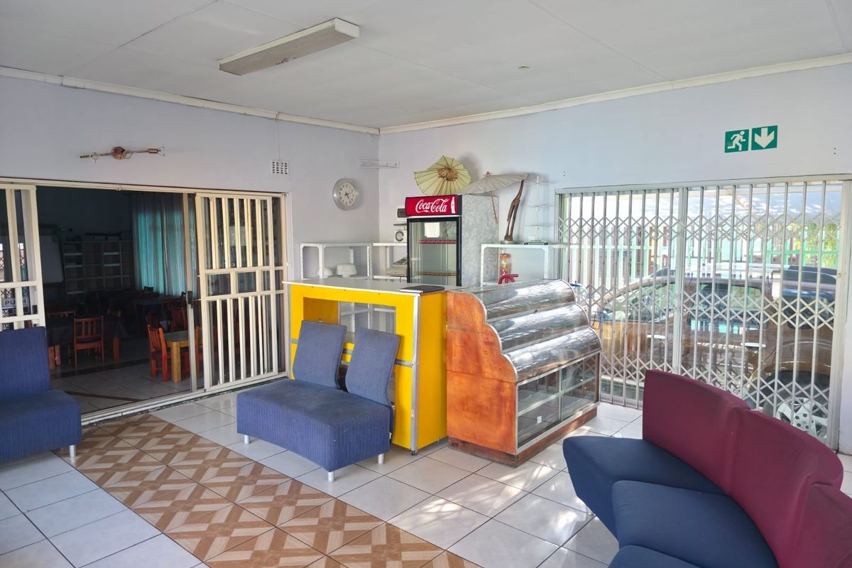 Spacious commercial interior featuring tiled flooring, security gates, and sliding door access, suitable for a reception or waiting area.