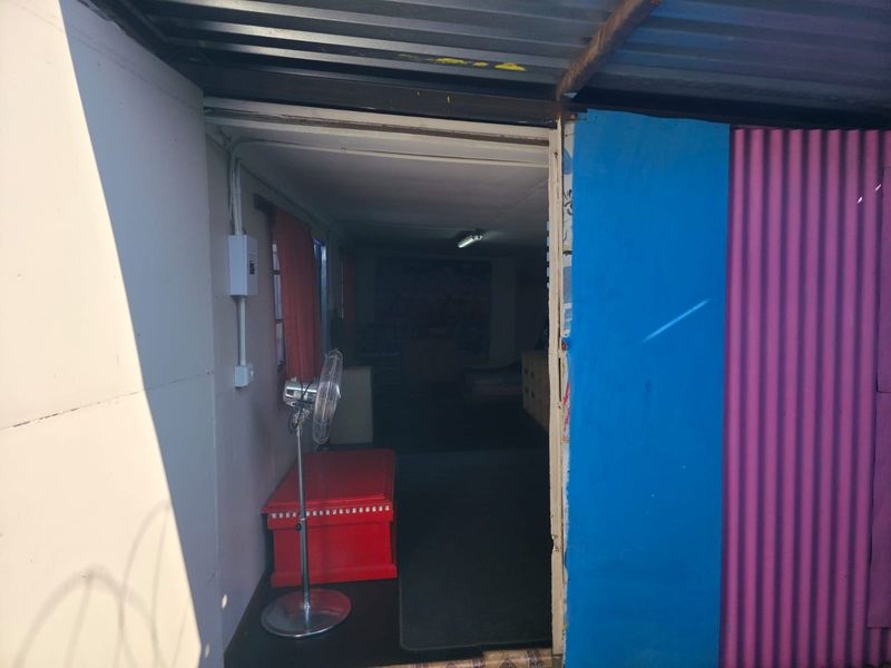 Entrance view of a structure featuring corrugated metal cladding and roofing, showing signs of wear and basic construction.