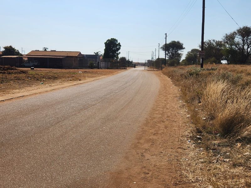 A view of the paved street frontage providing access to the commercial vacant land, featuring utility infrastructure and surrounding neighborhood context.