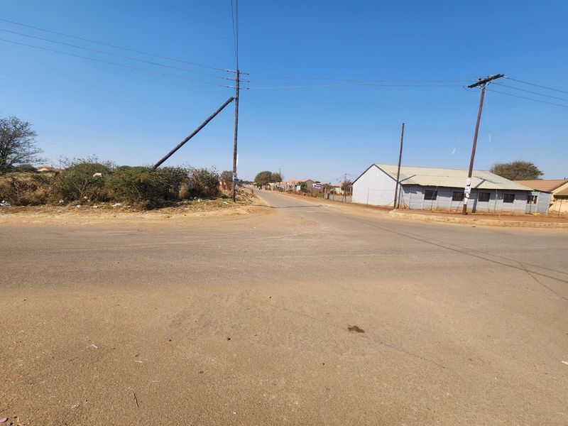 A street view showing an intersection with asphalt roads, utility poles, and overhead power lines in a commercial area.