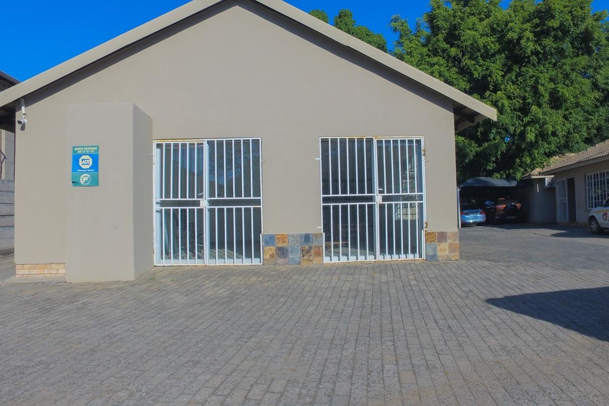 Front exterior view of the office building featuring a paved driveway, stone cladding accents, and secure metal entrance gates.