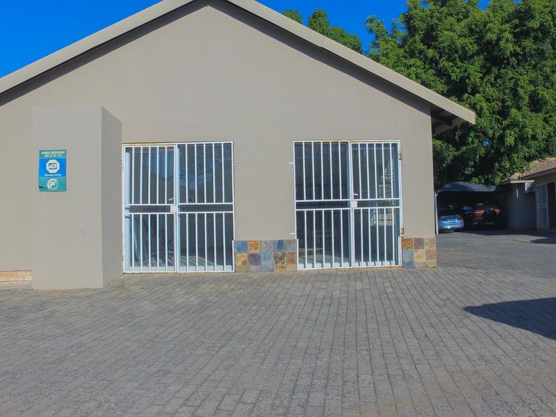 Front exterior view of the office building featuring a paved driveway, stone cladding accents, and secure metal entrance gates.