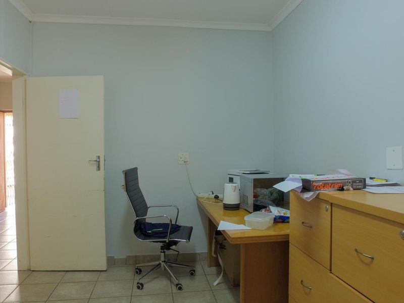 A functional office space featuring tiled flooring, a built-in desk, and neutral wall finishes, suitable for a professional work environment.