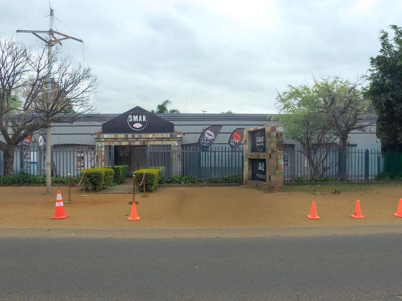 Front exterior view of the office property featuring a stone-clad entrance, secure perimeter fencing, and prominent signage.