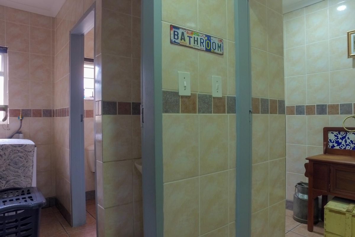 A functional bathroom area featuring neutral ceramic wall and floor tiling with decorative border accents and integrated light switches.