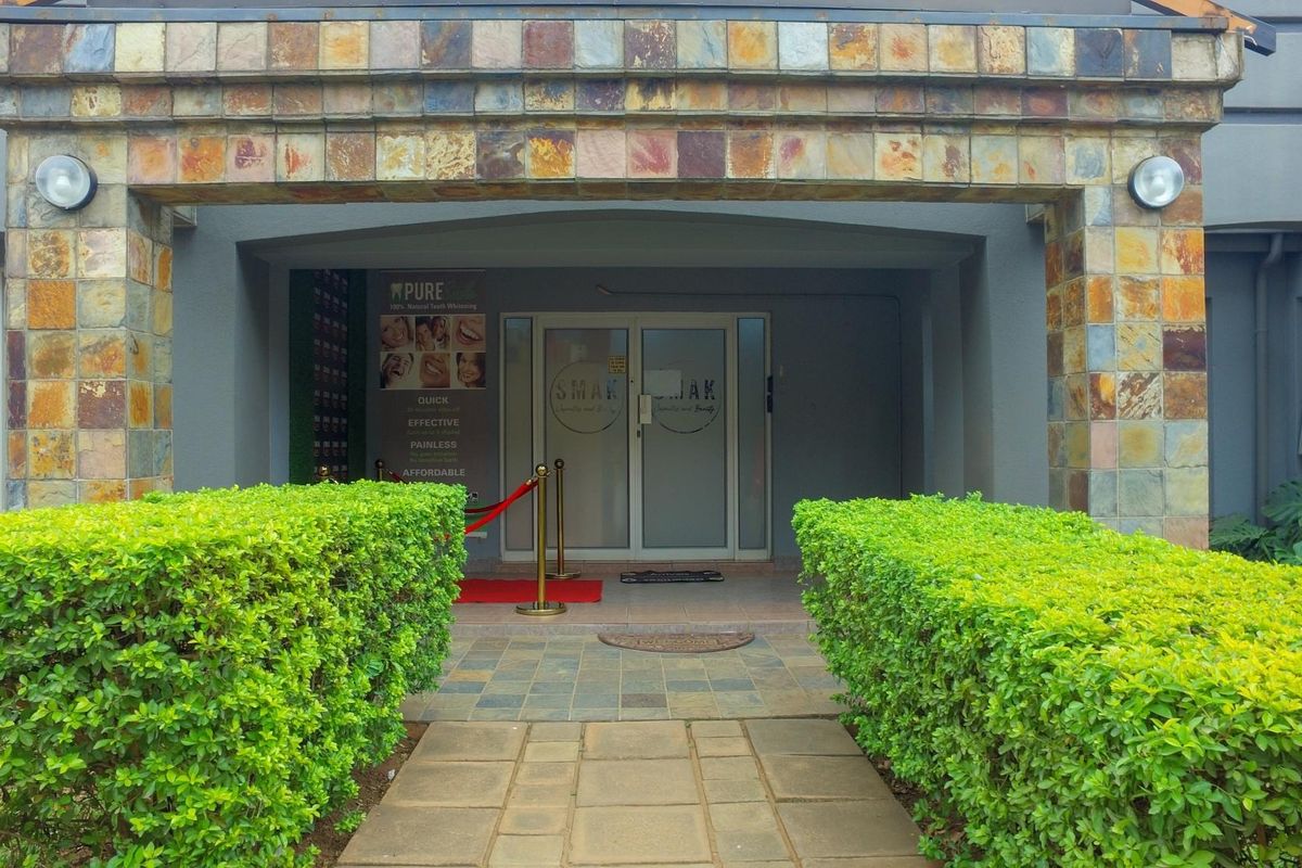 Front entrance of the office building featuring stone cladding, paved walkway, and glass double doors.