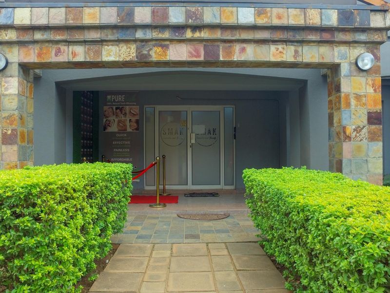 Front entrance of the office building featuring stone cladding, paved walkway, and glass double doors.