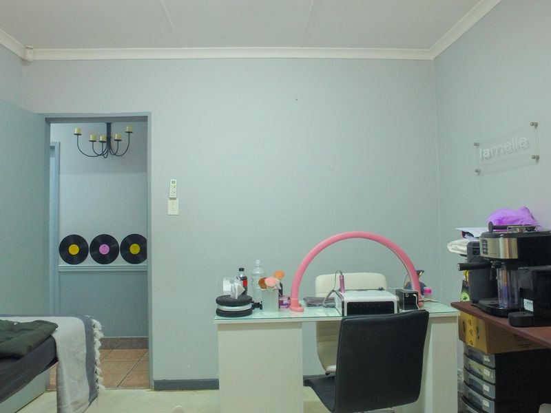 A functional office space featuring neutral wall finishes, coving, and a doorway leading to an adjacent room.