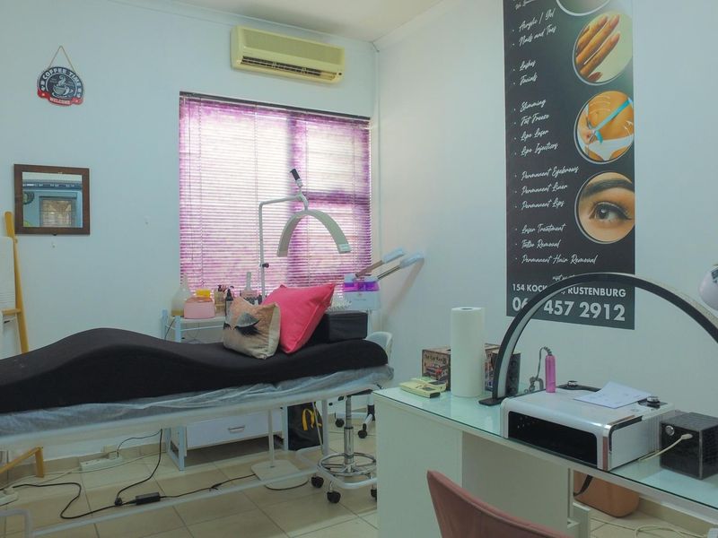 A functional office or treatment room featuring tiled flooring, a wall-mounted air conditioning unit, and window blinds.