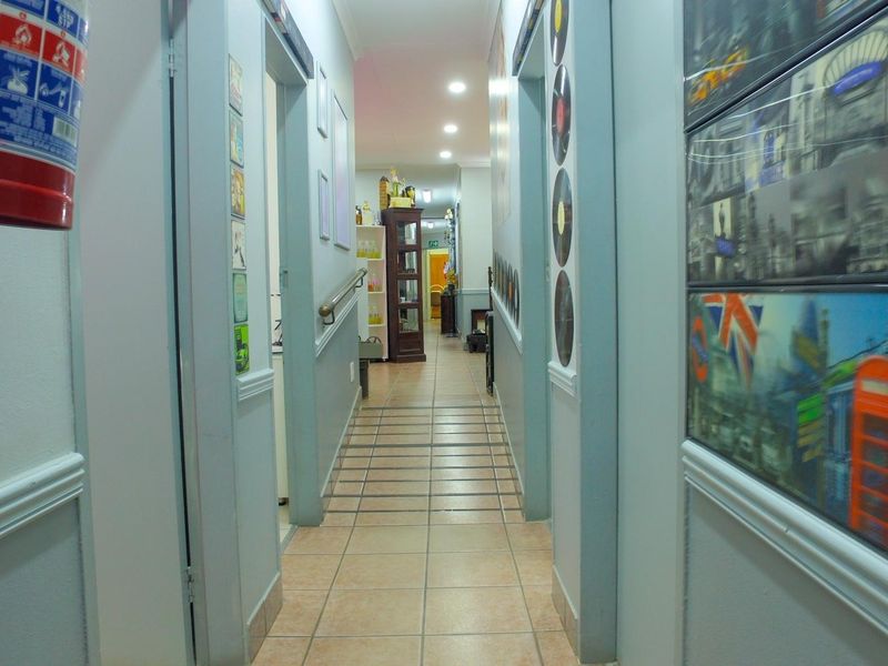 A functional office hallway featuring tiled flooring, recessed lighting, and a wall-mounted fire extinguisher, providing access to multiple office spaces.