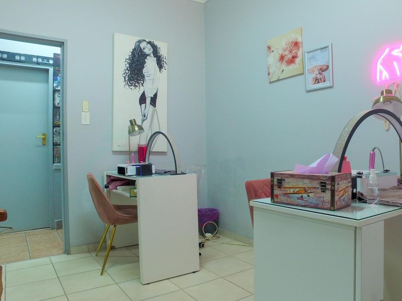 A functional office space featuring tiled flooring and a neutral wall finish, currently utilized as a beauty or nail treatment room.