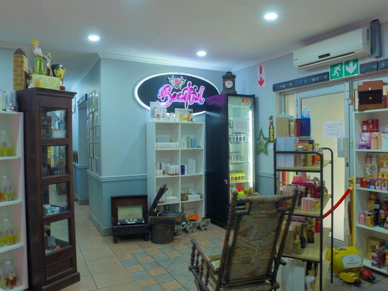 A well-lit commercial office space featuring tiled flooring, recessed ceiling lights, and a wall-mounted air conditioning unit, currently utilized for retail display.