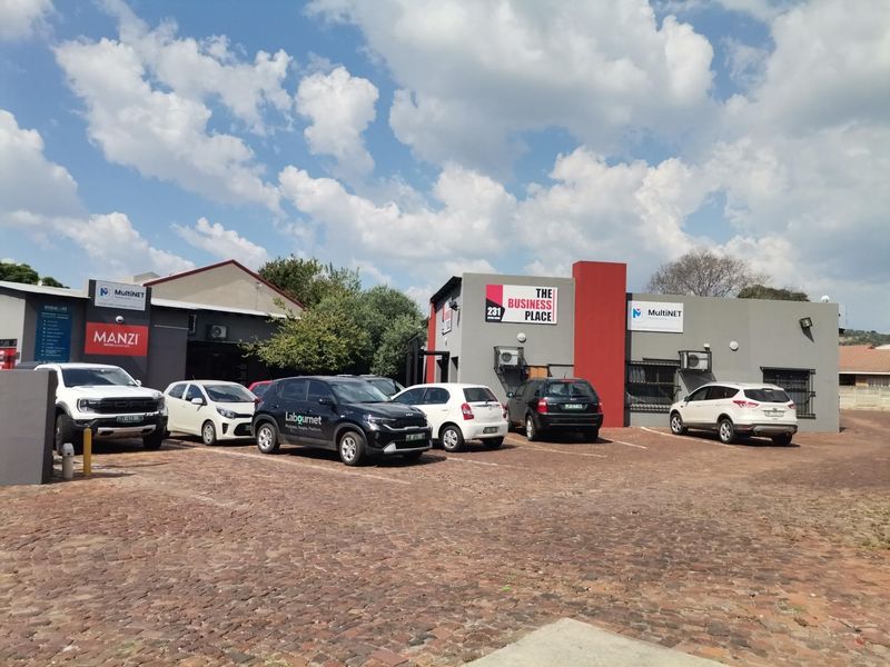 Front exterior view of a commercial office complex featuring a paved parking area and multiple business signage displays.