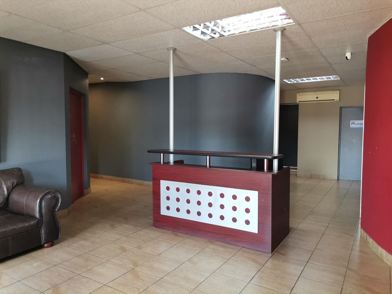 Office reception area featuring a built-in reception desk, ceramic tiled flooring, and suspended ceiling with integrated lighting.