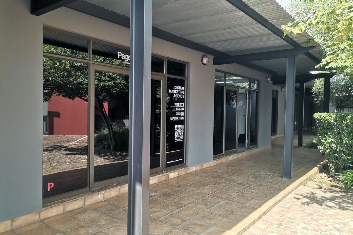 Front exterior view of an office unit featuring a covered walkway with tiled flooring and large aluminium-framed glass entrance doors.