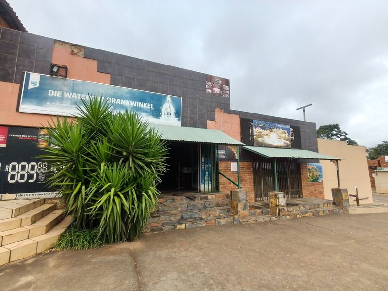 Front exterior view of a commercial guest house building featuring stone-clad stairs, metal awnings, and prominent signage.