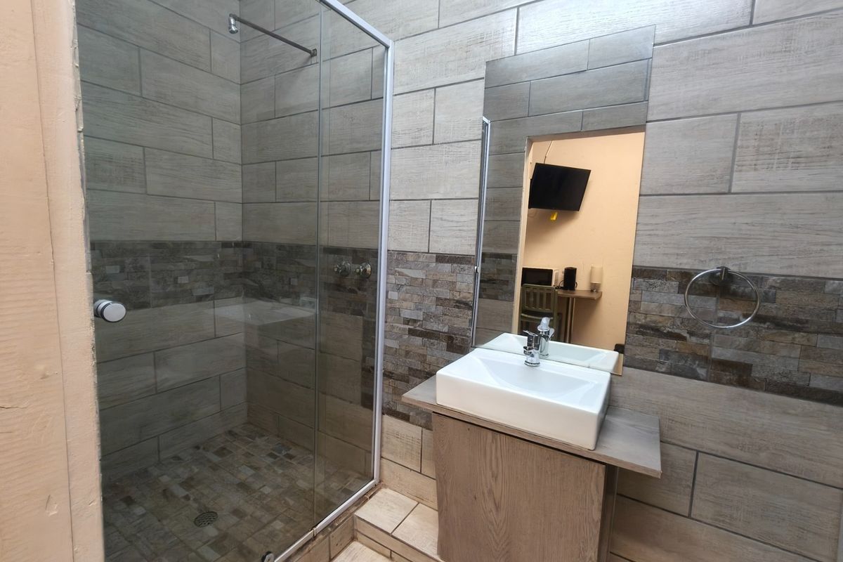 Modern bathroom featuring a glass-enclosed shower, vessel sink with vanity cabinet, and contemporary tiled walls.