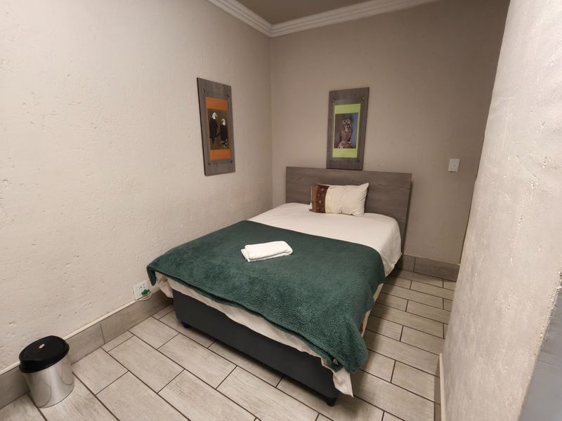 A compact bedroom featuring tiled flooring and neutral wall finishes, providing a functional space for guests.