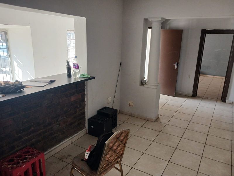 Open plan living area featuring a brick breakfast bar, ceramic tiled flooring, and a decorative column, offering a versatile space for industrial or commercial use.