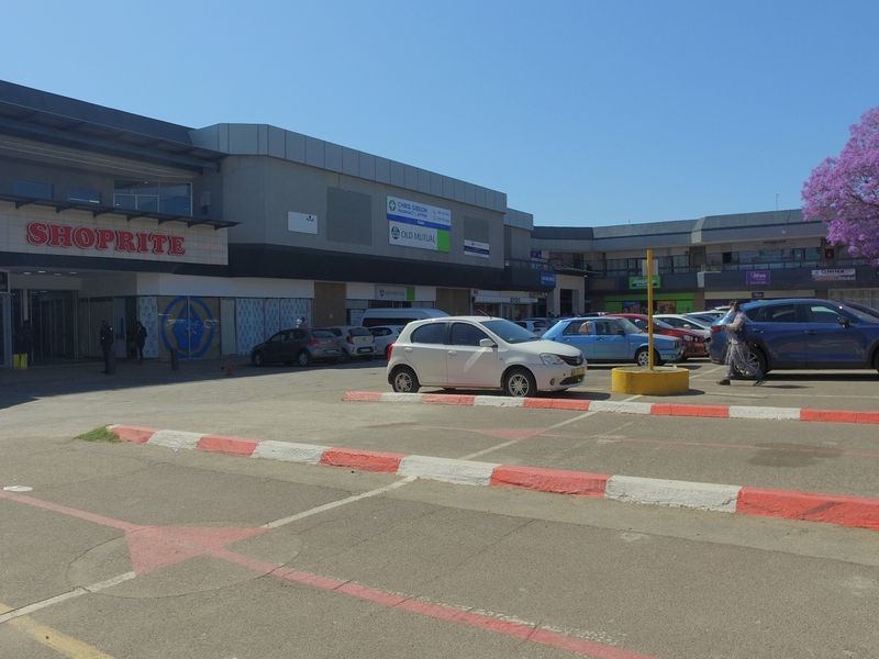 Exterior view of a commercial shopping center featuring a large parking area and multiple storefronts with prominent signage.