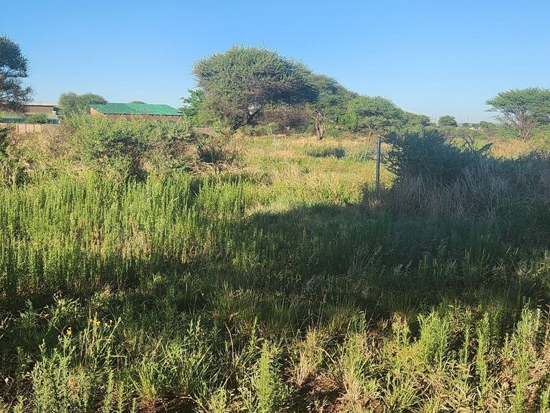 A view of a vacant commercial land plot featuring natural vegetation and perimeter fencing, suitable for future development.