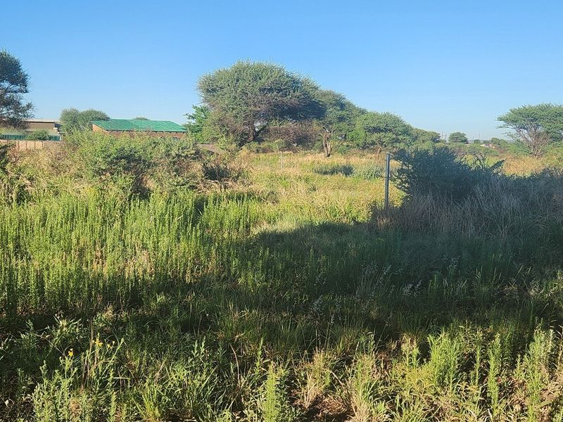 A view of a vacant commercial land plot featuring natural vegetation and perimeter fencing, suitable for future development.