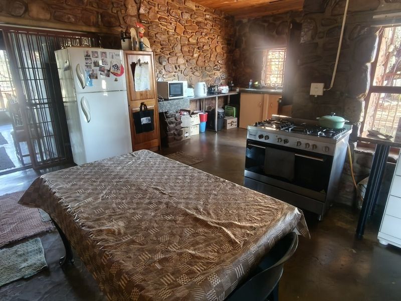 Rustic kitchen featuring exposed stone walls, timber ceiling, and a gas stove, offering a traditional farm-style aesthetic with potential for modernization.