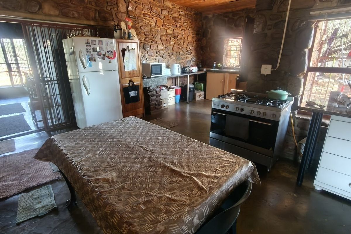 Rustic kitchen featuring exposed stone walls, timber ceiling, and a gas stove, offering a traditional farm-style aesthetic with potential for modernization.