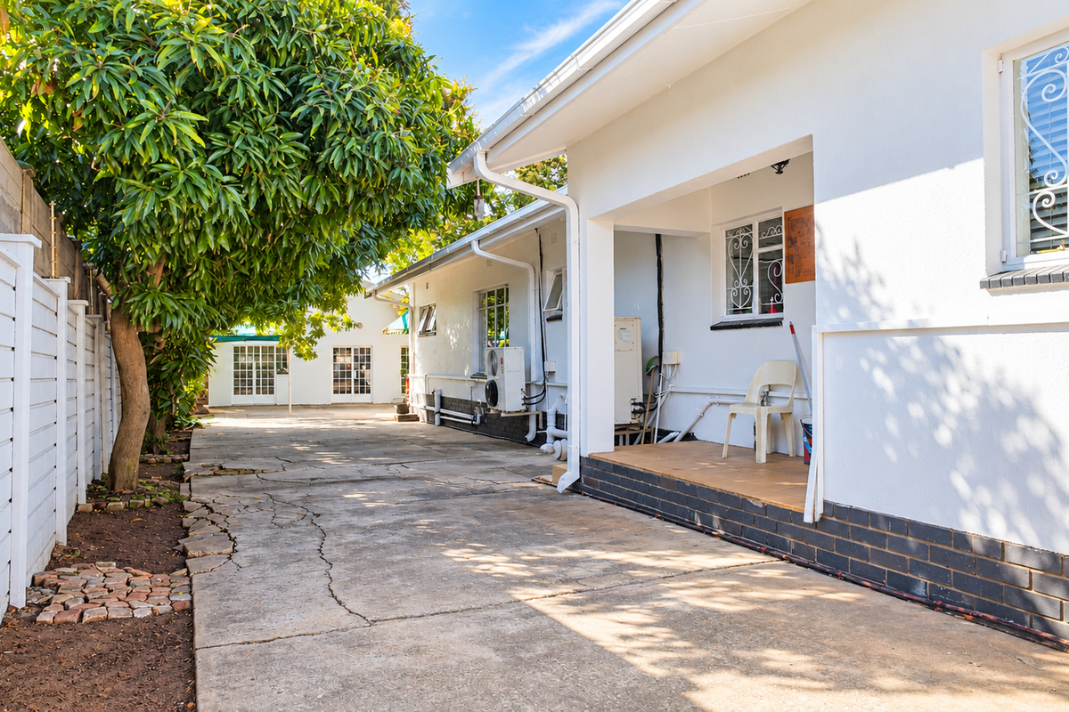 Rear exterior view of the office property featuring a concrete driveway, covered patio area, and secure boundary walling.