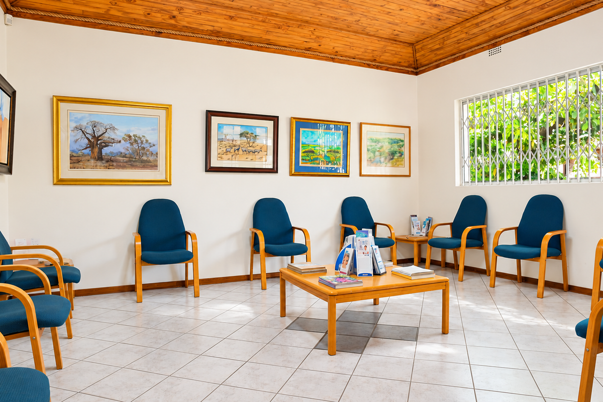 A well-maintained office waiting area featuring ceramic tile flooring, a warm timber ceiling, and a large window with security bars.