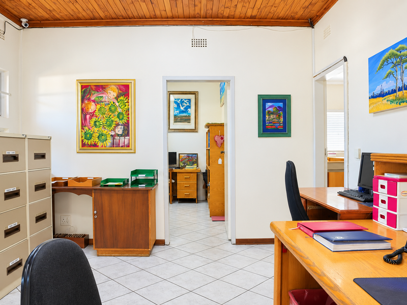 A functional office space featuring tiled flooring, a timber ceiling, built-in filing cabinets, and a wall-mounted air conditioning unit.