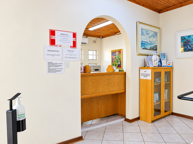 Office reception area featuring a built-in wooden desk, tiled flooring, and a distinctive arched entryway with timber ceiling finishes.