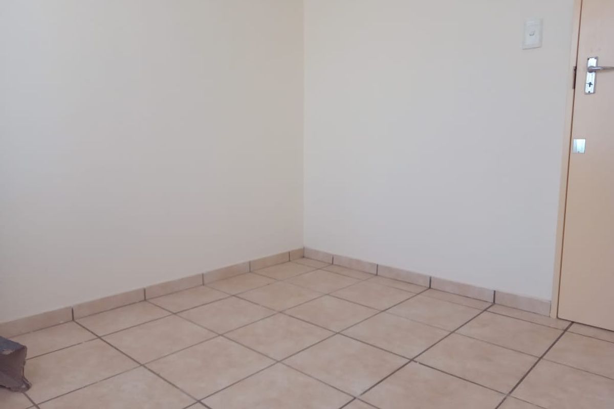 A clean, empty room featuring neutral tiled flooring and a standard interior door, providing a versatile space ready for customization.