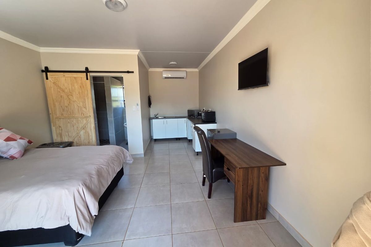 Open-plan studio apartment featuring a kitchenette, tiled flooring, split-system air conditioning, and a sliding barn door leading to the bathroom.