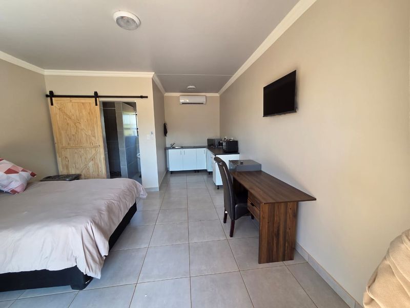 Open-plan studio apartment featuring a kitchenette, tiled flooring, split-system air conditioning, and a sliding barn door leading to the bathroom.