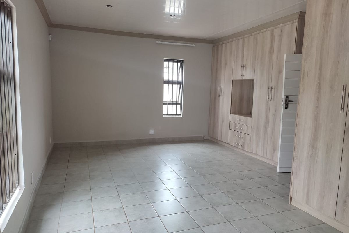 Spacious bedroom featuring neutral tiled flooring, recessed ceiling lighting, and extensive built-in wooden cabinetry for ample storage.