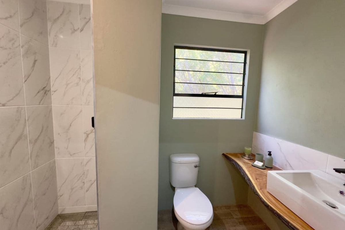 Modern bathroom featuring a walk-in shower with marble-look tiling, a unique live-edge timber vanity with a vessel sink, and a toilet.