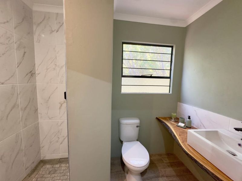 Modern bathroom featuring a walk-in shower with marble-look tiling, a unique live-edge timber vanity with a vessel sink, and a toilet.
